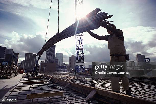 crane lowering girders to two builders - lowering photos et images de collection