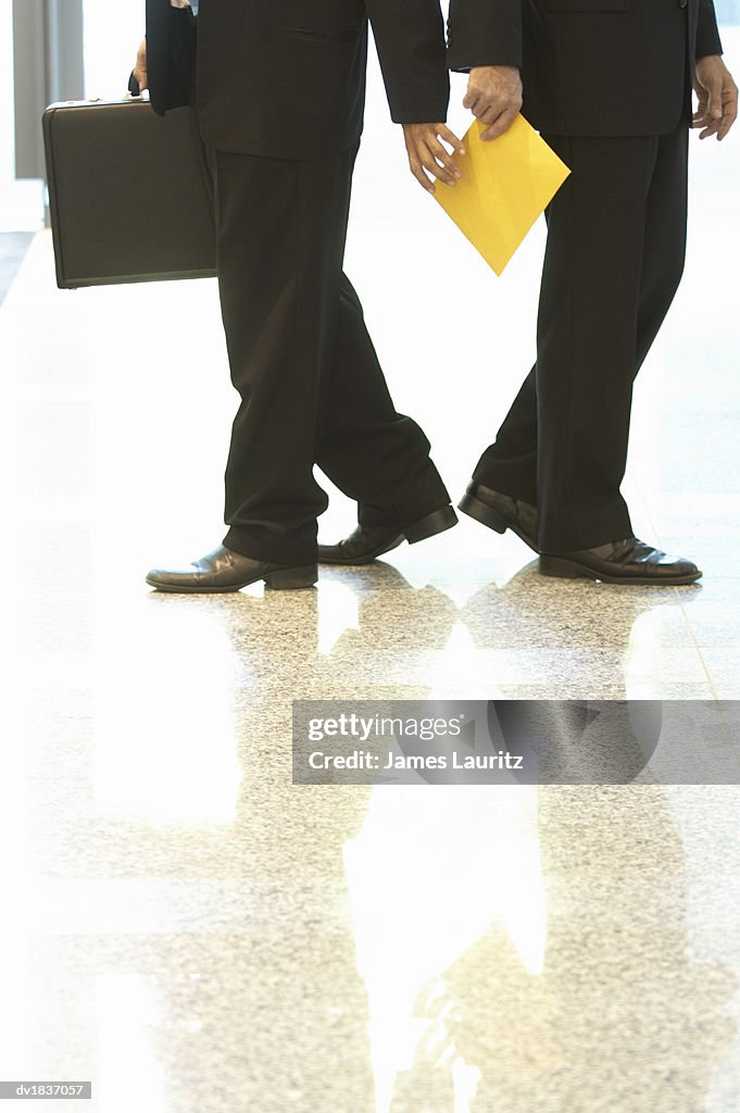 Low Section of a Businessman Handing an Envelope To Another Businessman