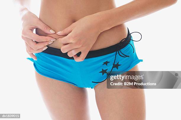 woman wearing blue knickers pinching her stomach - knickers stock pictures, royalty-free photos & images