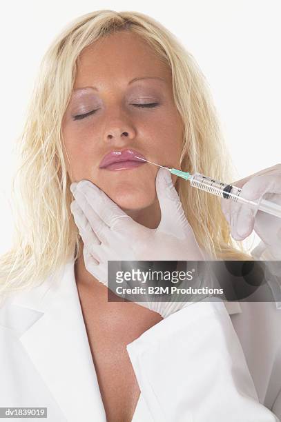 woman receiving cosmetic surgery from a syringe - anatomical substance foto e immagini stock