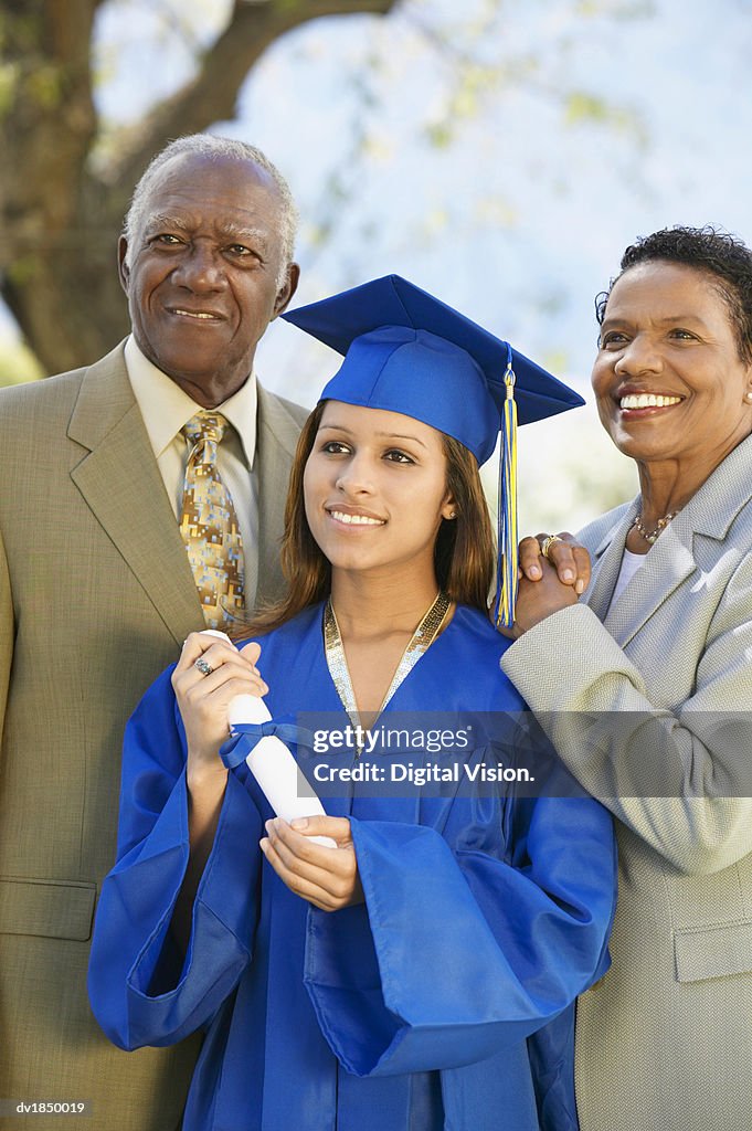 Proud Parents Outdoors With Their Daughter on Graduation Day