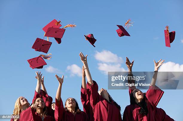 line of female students throwing their mortar boards in the air at graduation - mortelplank stockfoto's en -beelden