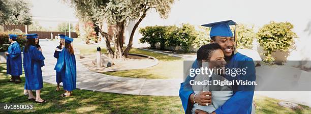 mother and son hugging on campus at his graduation - traje academico imagens e fotografias de stock