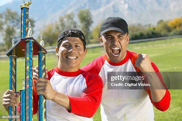 baseball players holding a trophy - baseball trophy stock pictures, royalty-free photos & images