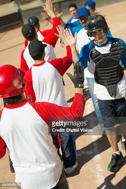 line of baseball players giving each other high fives - fives stock-fotos und bilder