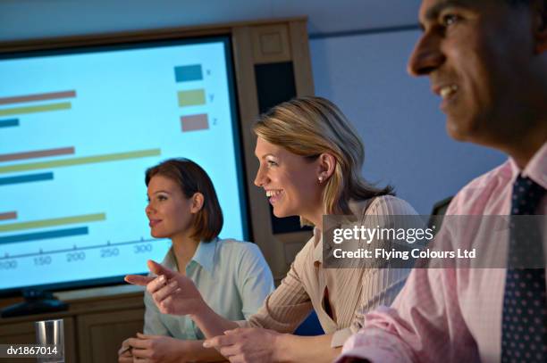 businesswoman sitting between colleagues and pointing during a meeting - beed stock pictures, royalty-free photos & images