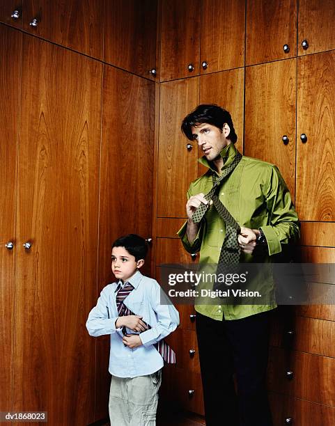 father standing beside his son, both looking in the mirror tying ties - digital devices beside each other bildbanksfoton och bilder