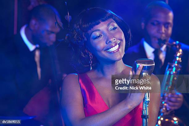 female jazz singer performs by a retro microphone, jazz band in the background - afroamerikansk kultur bildbanksfoton och bilder