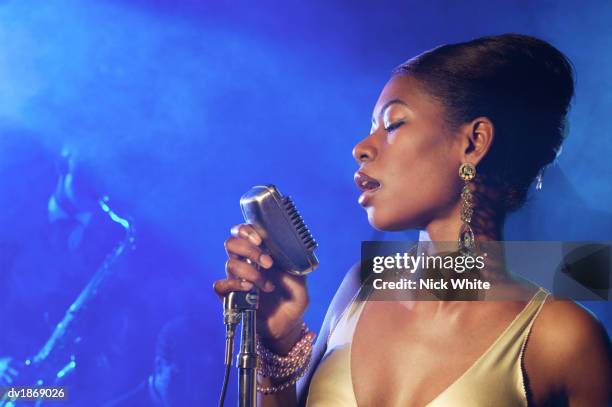 female jazz singer standing with a microphone in front of a man playing an alto saxophone - beehive hair ストックフォトと画像