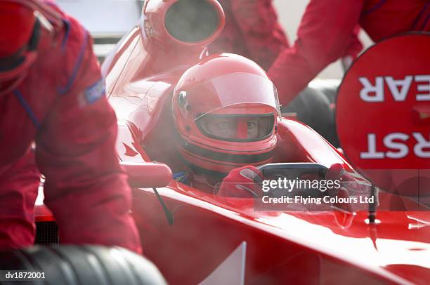 professional sports driver sitting in a open-wheel single-seater racing car racing car as mechanics perform a pit stop - ['sports car' stock pictures, royalty-free photos & images