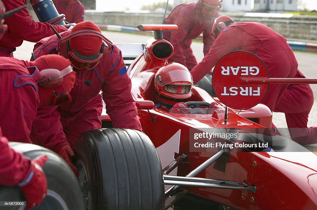 Open-wheel single-seater racing car Driver Sitting in a Racing Car as His Mechanics Perform a Pit Stop
