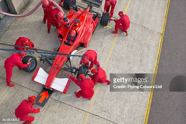 elevated view of a pit stop mechanics working on a formula one racing car - match sport stockfoto's en -beelden