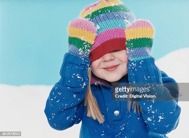 studio portrait of a young girl hiding under her woolen hat - mitten foto e immagini stock