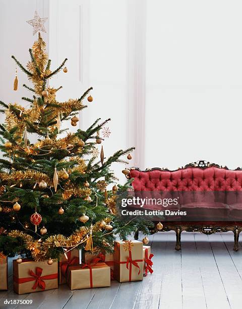 decorated christmas tree with wrapped presents underneath next to a chaise lounge - next to stock pictures, royalty-free photos & images