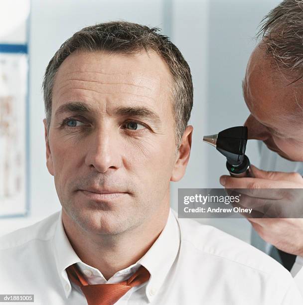 doctor examining a patients ear with an otoscope - olney md stock pictures, royalty-free photos & images