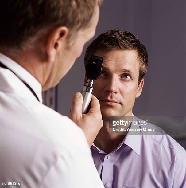 doctor examining a patient's eye with a strabismoscope - olney md stock pictures, royalty-free photos & images