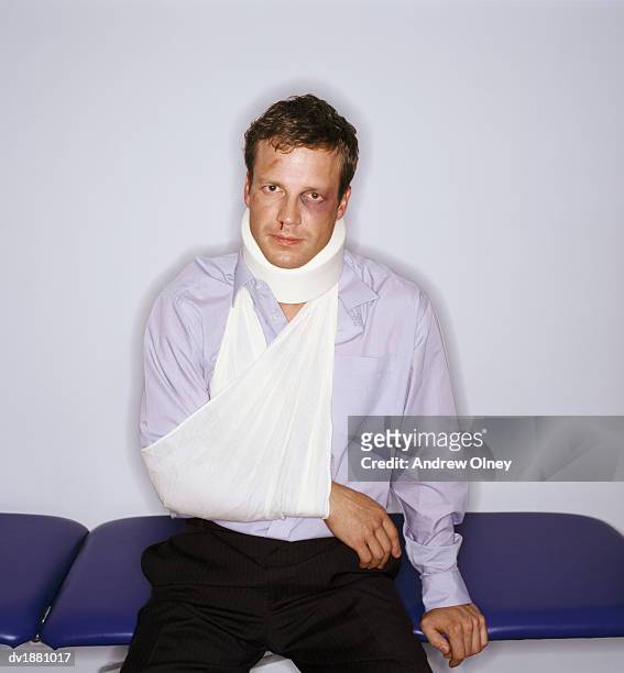 injured man wearing a neck brace and arm sling - collarín médico fotografías e imágenes de stock
