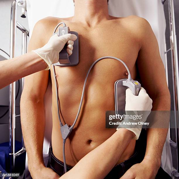 viewed from directly above of a defibrillator being held on a man's bare chest - olney md stock pictures, royalty-free photos & images