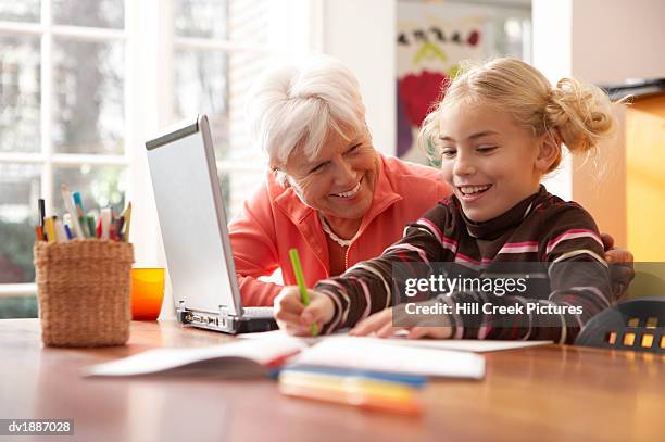 grandmother watching her granddaughter draw with colouring pencils - colouring fotografías e imágenes de stock