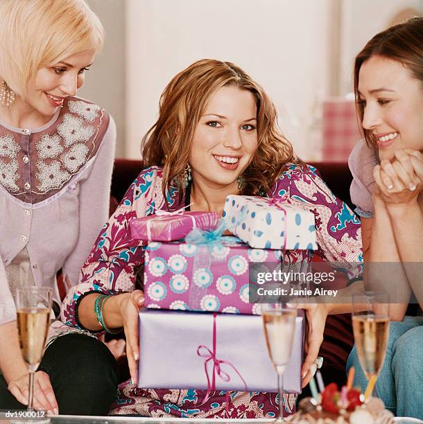 woman sits between her friends holding a pile of wrapped birthday presents and smiling - wrap blouse stock pictures, royalty-free photos & images