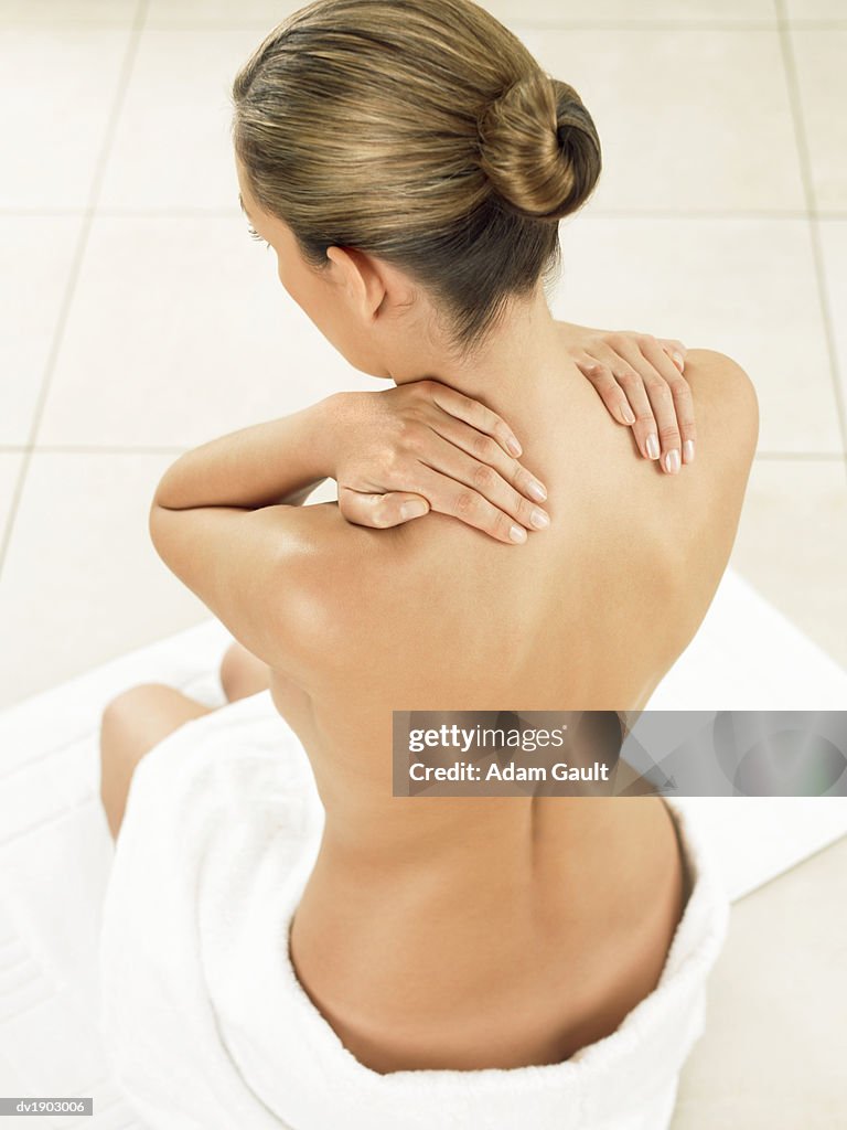 Woman Sitting in Bathroom Massaging Her Neck