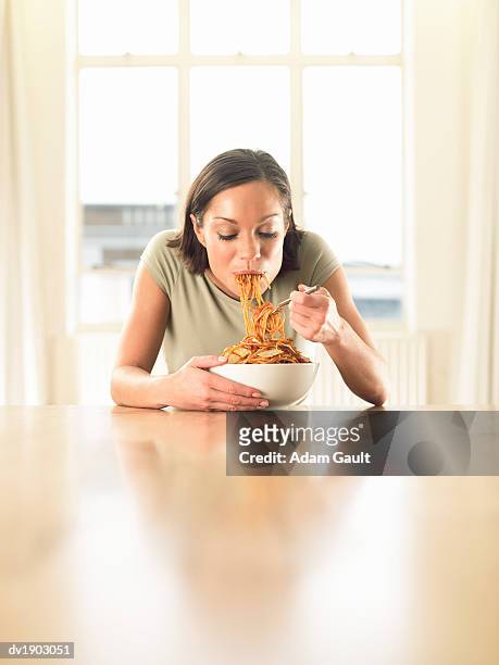 thirty something woman sitting at a dining table eating spaghetti - adam hunger fotografías e imágenes de stock
