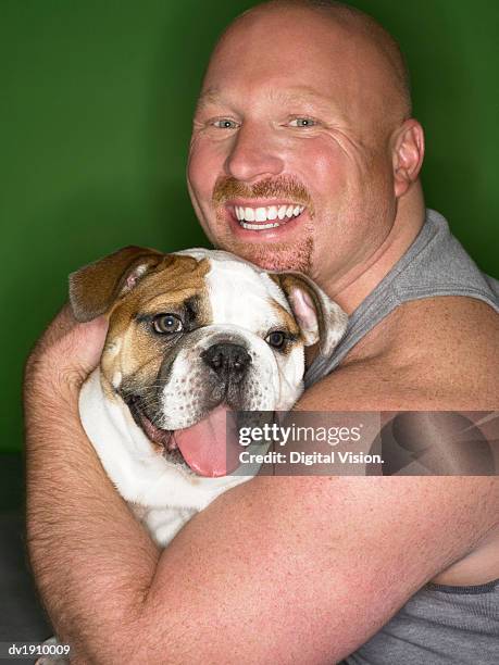 studio portrait of a man hugging his bulldog - animal macho 個照片及圖片檔