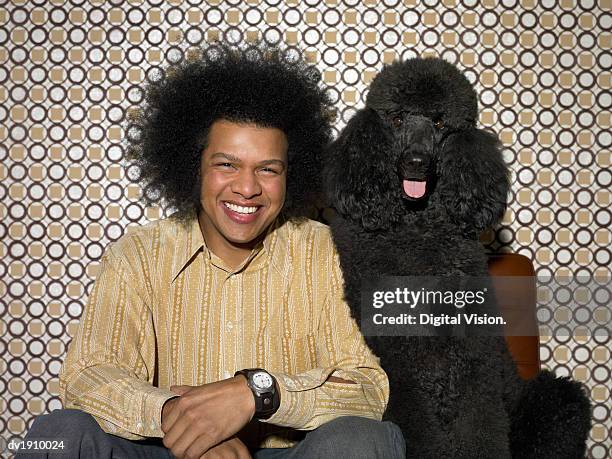 man with an afro sitting next to a black poodle - rappresentare foto e immagini stock