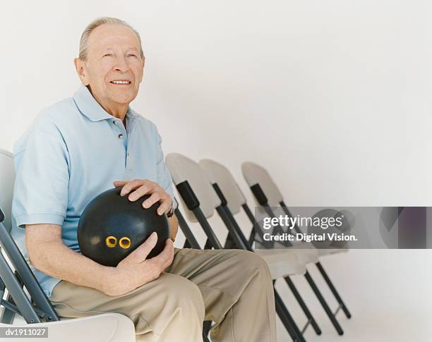 senior man sits on a chair holding a bowling ball - ball chair stock pictures, royalty-free photos & images