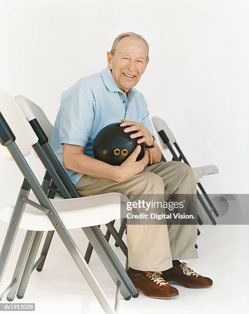 senior man sits on a chair holding a bowling ball - bowling ball on white stock pictures, royalty-free photos & images