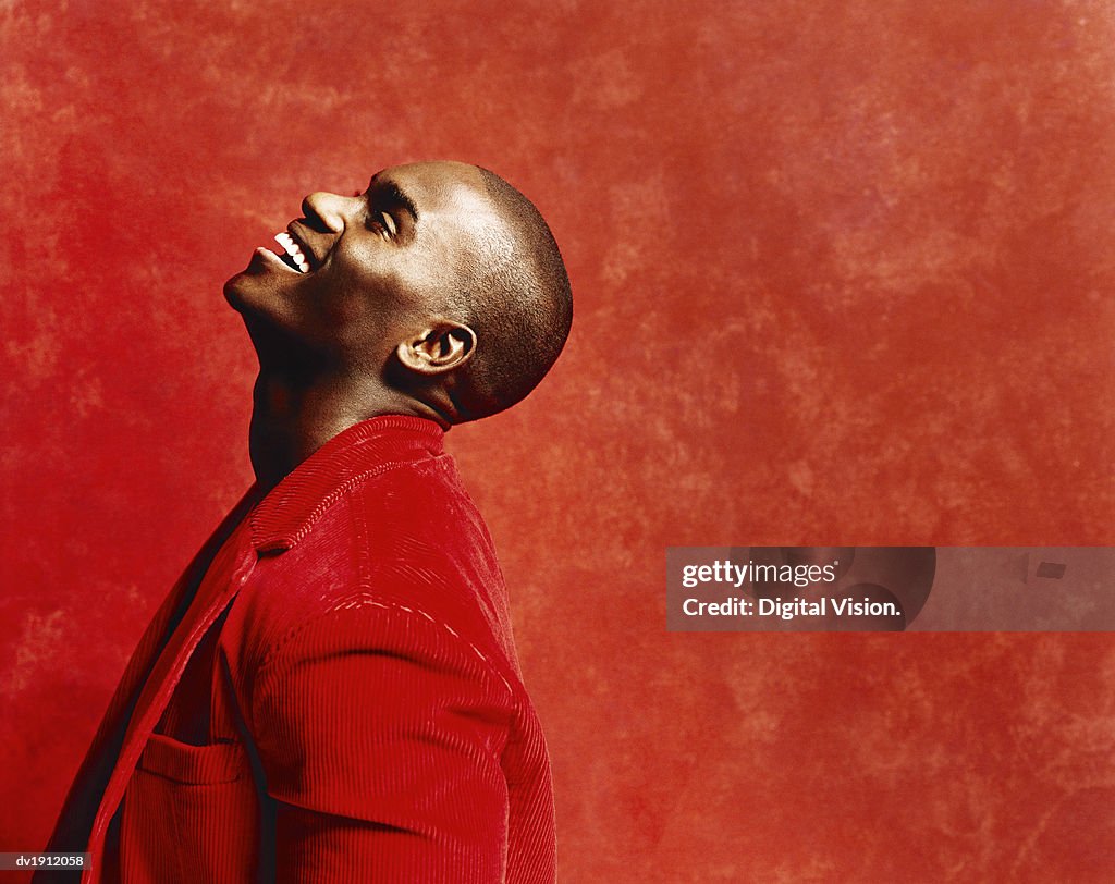 Studio Shot of a Young Man in a Casual Red Jacket, Laughing and Looking Upwards
