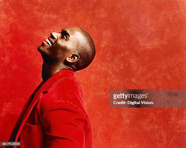 studio shot of a young man in a casual red jacket, laughing and looking upwards - corduroy stockfoto's en -beelden