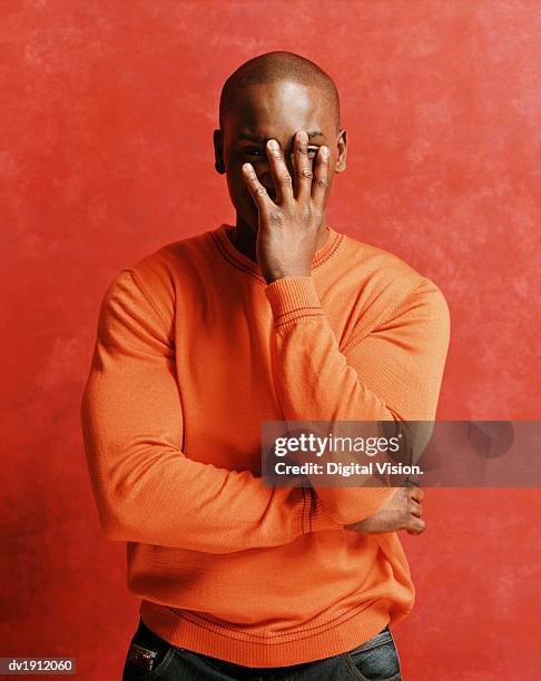 portrait of an embarrassed man, peeking from behind his hand - embarrassment stock pictures, royalty-free photos & images