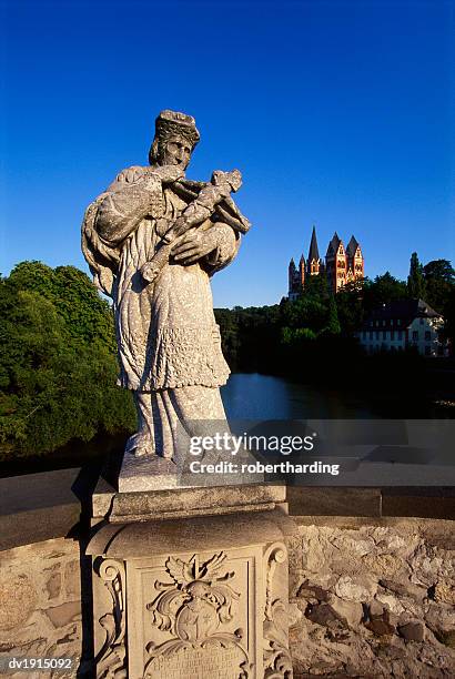statue on the old lahn-bridge and a cathedral beyond a forrest in limburg,  germany - old cathdral stock pictures, royalty-free photos & images