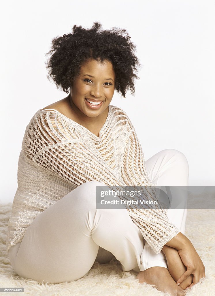 Studio Portrait of a Smiling Woman Sitting on a Rug