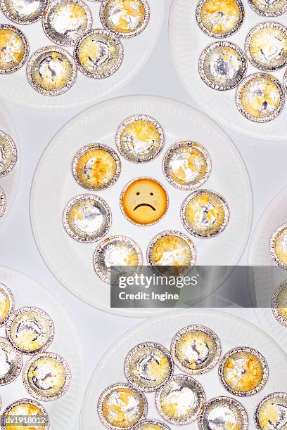 cupcake with a sad face amongst eaten cupcakes - bad cupcake stock pictures, royalty-free photos & images