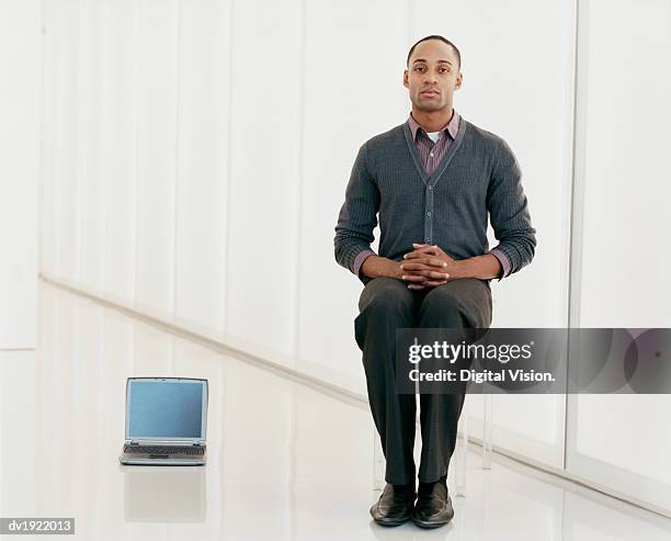 businessman sitting on a glass chair next to a laptop computer - digital devices beside each other bildbanksfoton och bilder