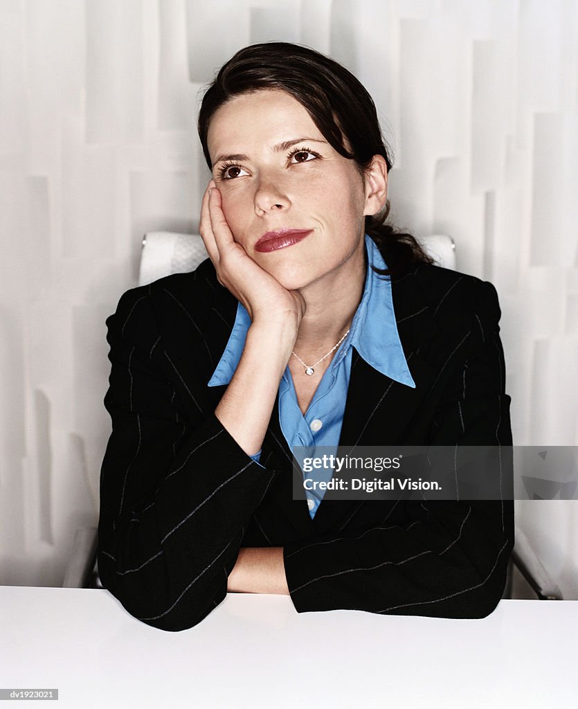 Thirty something Businesswoman Sitting Behind a Modern Desk Daydreaming