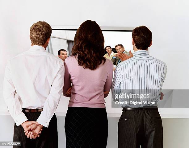 three business executives talking with colleagues via a video conference - via stock-fotos und bilder
