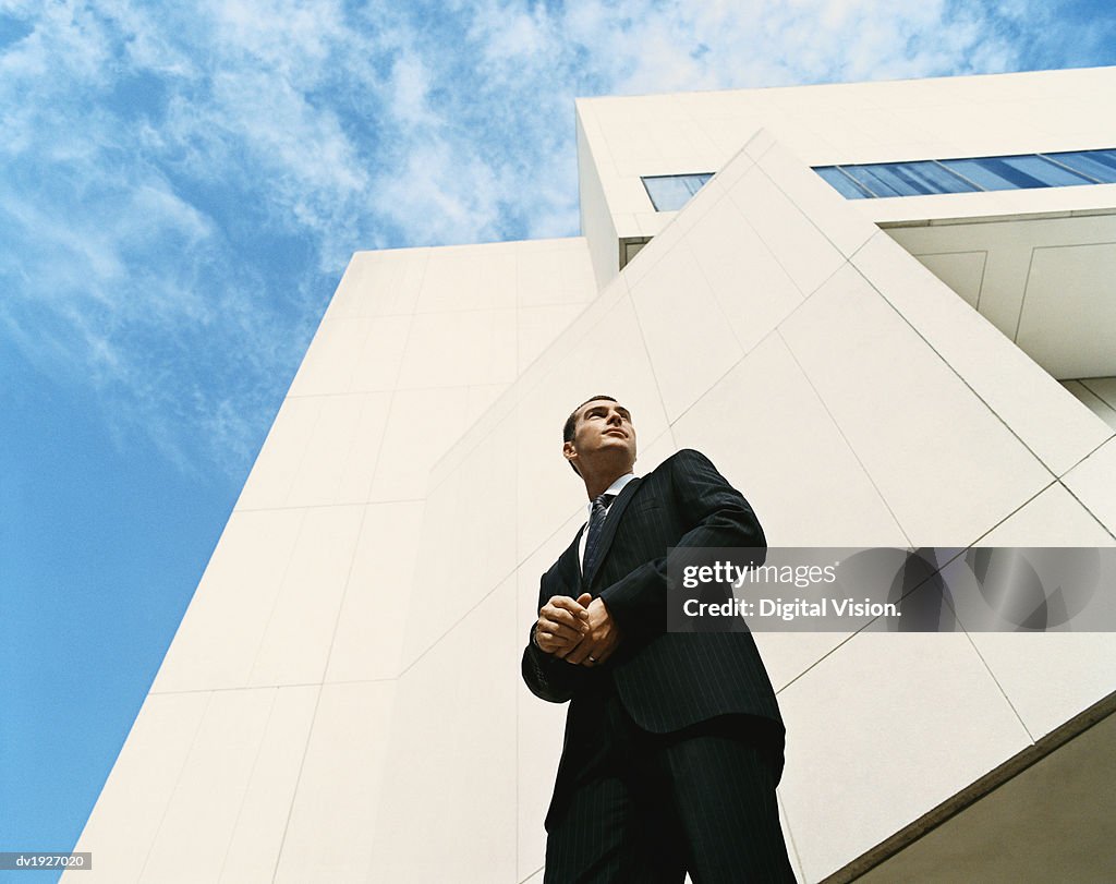 Businessman Looking Sideways Standing Outside a Modern Office Building