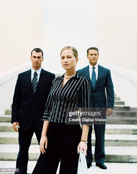 businesswoman standing on steps in front of two other business executives - portrait of young woman standing against steps imagens e fotografias de stock