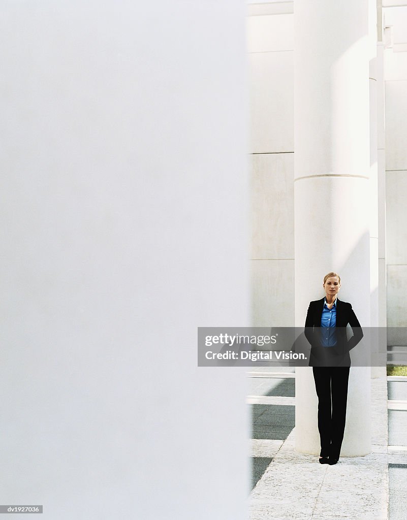 Distant View of a Businesswoman Leaning on a Pillar