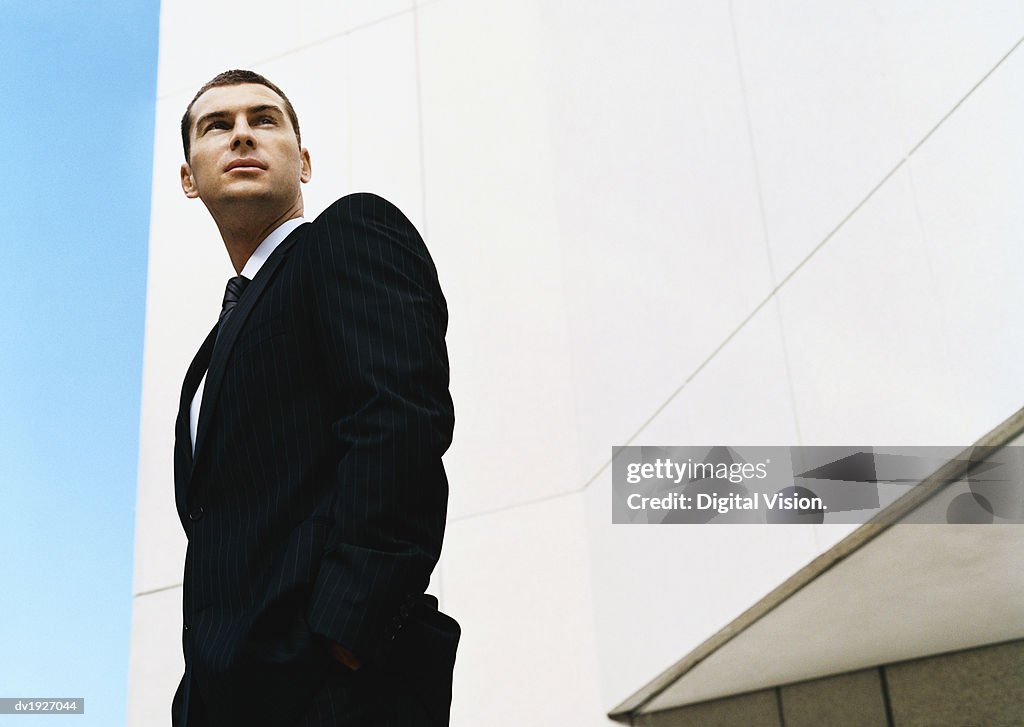 Low Angle Shot of a Businessman Standing by a Building With His Hands in His Pockets