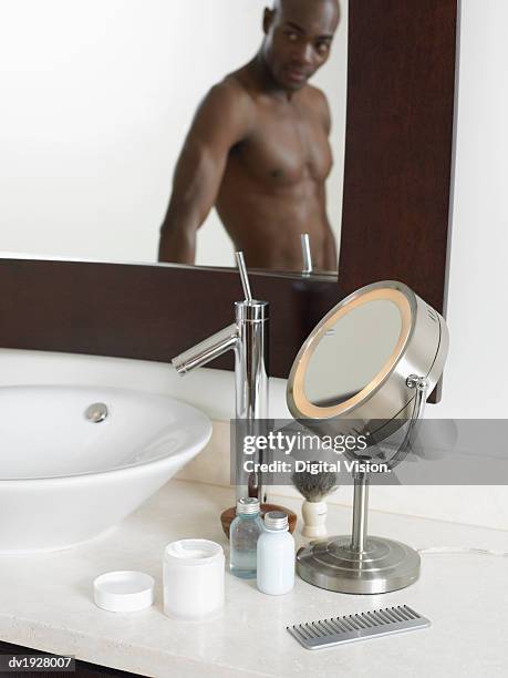 male grooming accessories in a bathroom, man looking at his reflection in a mirror - scheerkwast stockfoto's en -beelden
