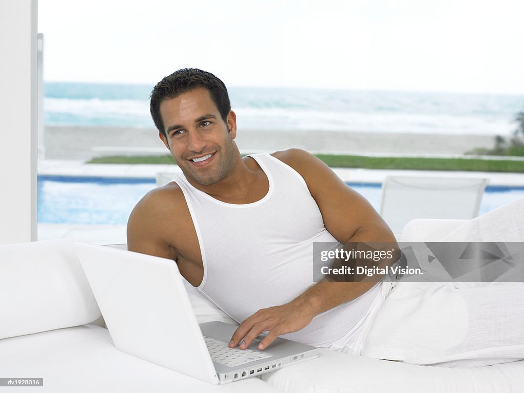 Close Up of a Man Lying on Sofa in His Pajamas Using His Laptop