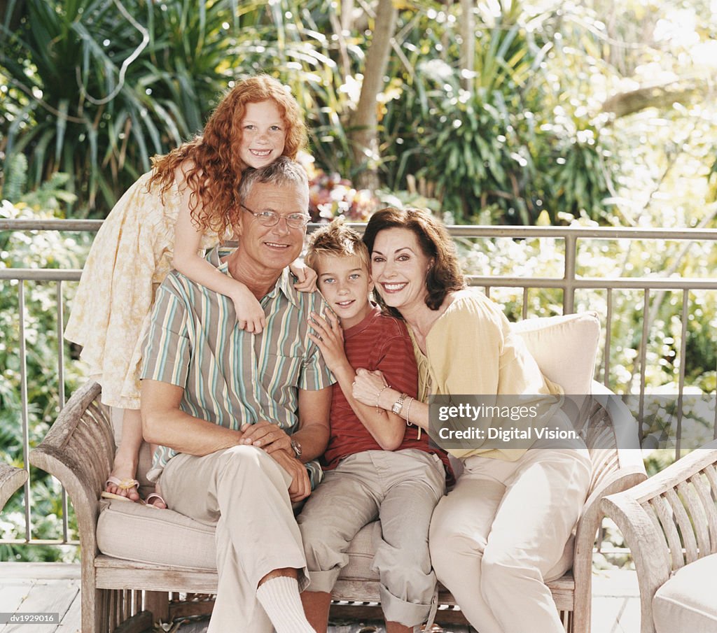 Portrait of a Family of Two Children Sitting on a Sofa on Their Porch