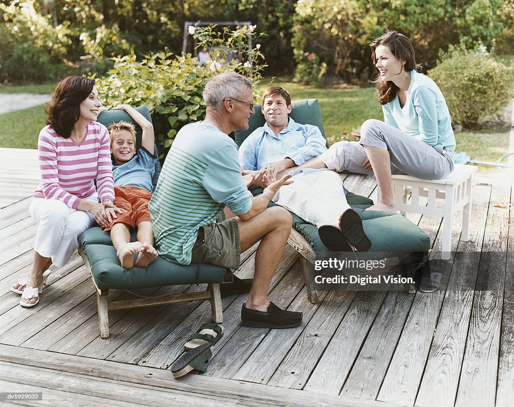 Three Generational Family Sit on Decking in Their Garden