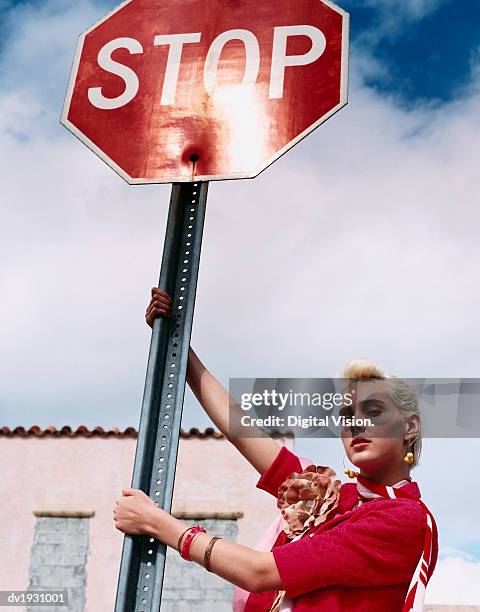 young woman with bleached hair and attitude holds a stop sign - digital devices beside each other bildbanksfoton och bilder