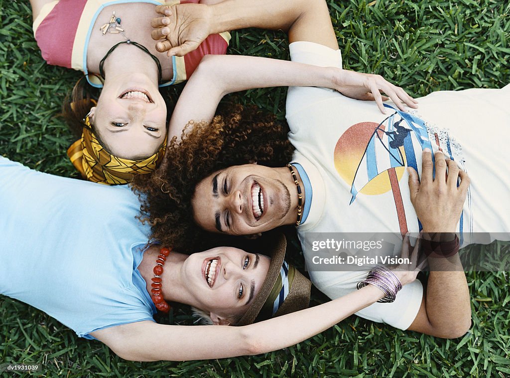 View Directly Above of Three Young Men and Women Lying on the Grass, Laughing