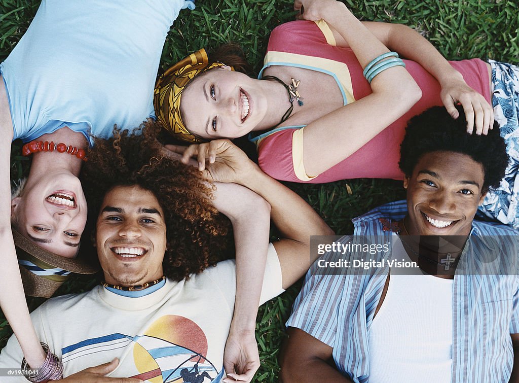 View Directly Above of Four Young Carefree Man and Women Lying on the Grass Close to Each Other
